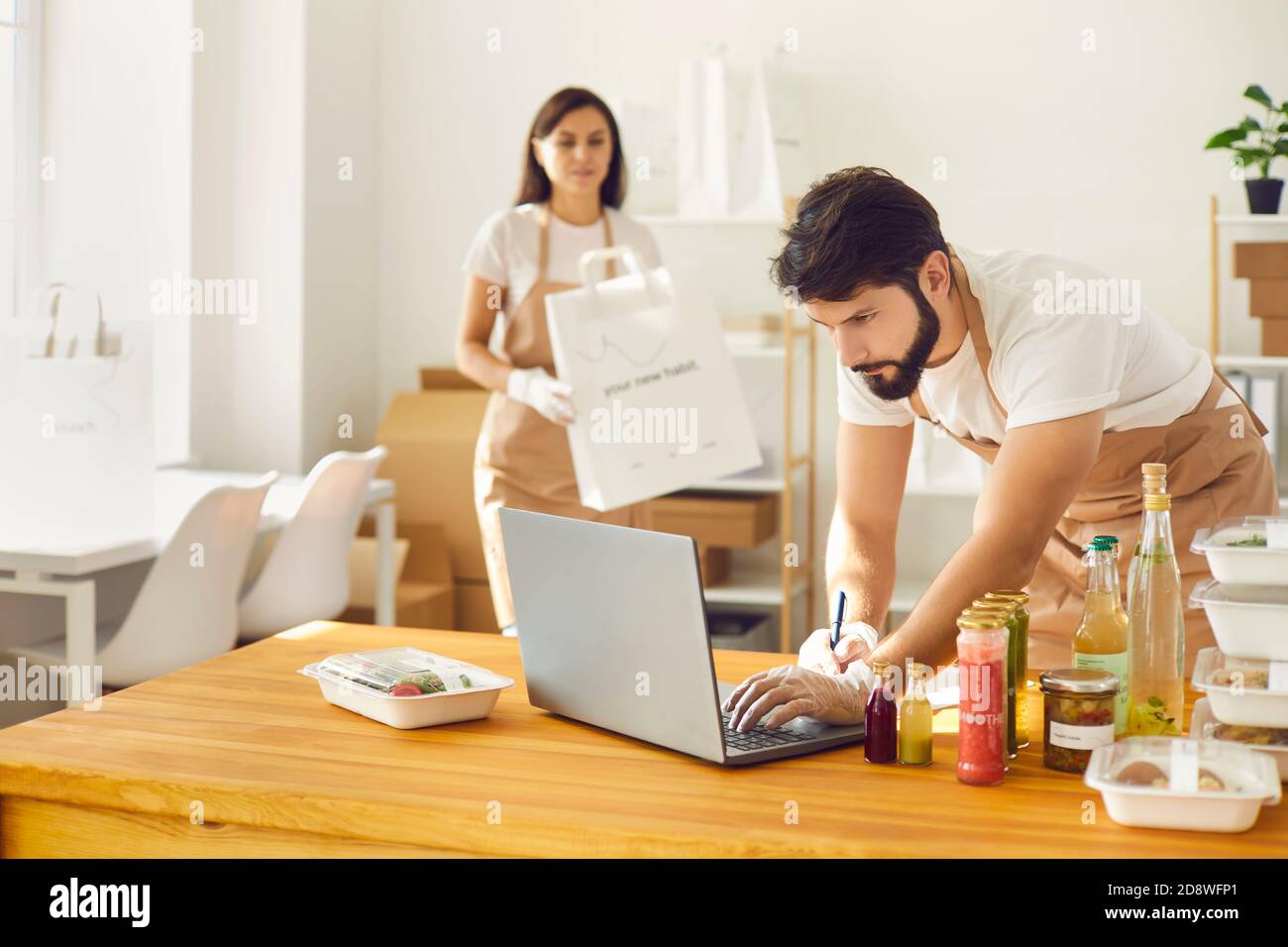 Les employés du café prennent des commandes en ligne et emballant des repas prêts à l'emploi contenants et sacs en papier Banque D'Images