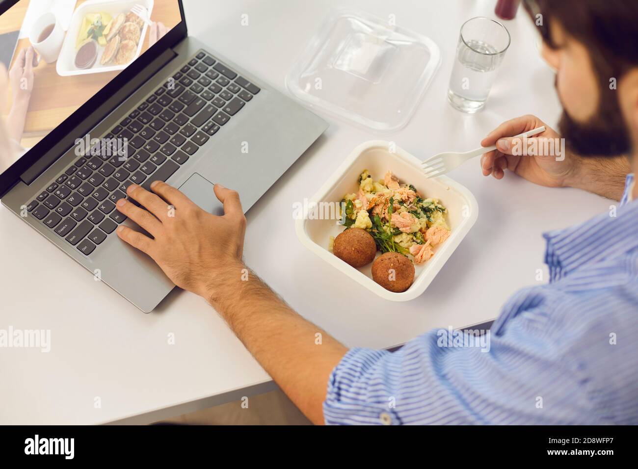 Homme ayant déjeuner dans le bureau, manger repas à emporter et visiter le  site Web de livraison de nourriture Photo Stock - Alamy