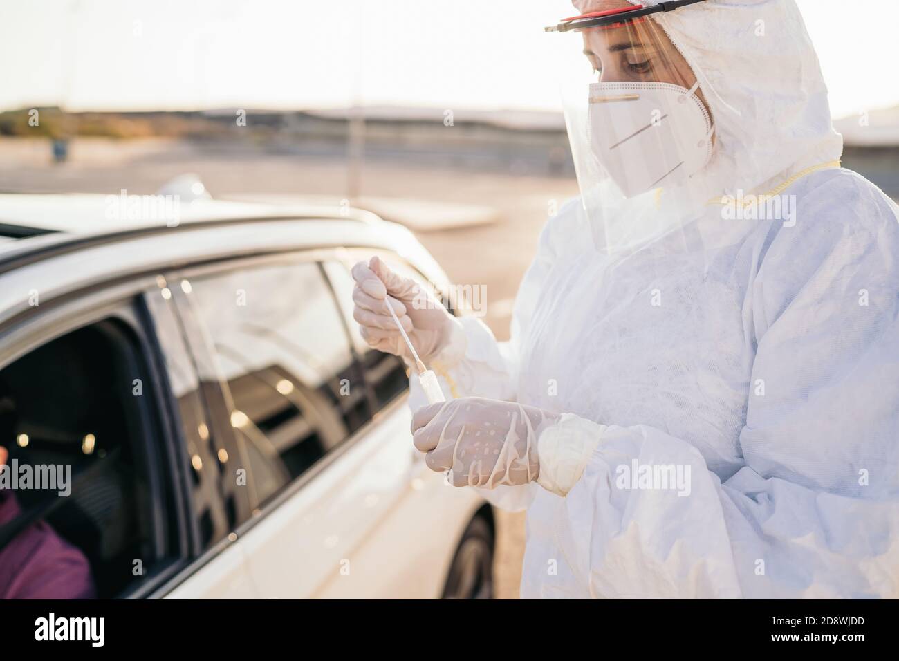 Médecin effectuant un test PCR COVID-19 sur un patient par la fenêtre de la voiture. Diagnostic PCR pour la présence de coronavirus, médecin dans la trousse de test de maintien des EPI Banque D'Images