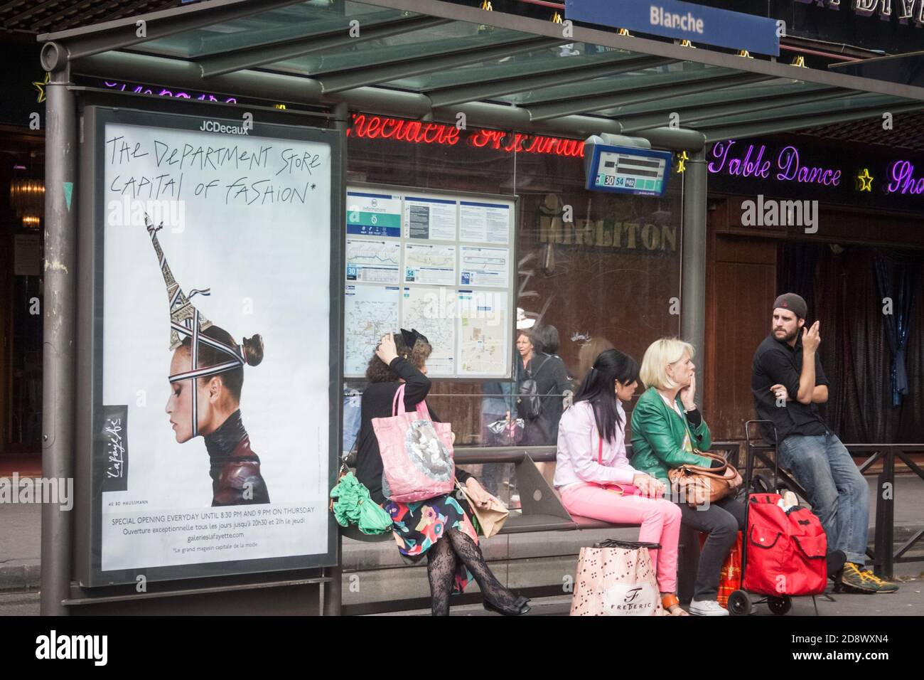 PARIS, FRANCE - 8 JUILLET 2014 : foule de personnes, navetteurs, attendant un bus de la compagnie RATP, le système de transit de bus de Paris, devant une affiche adv Banque D'Images