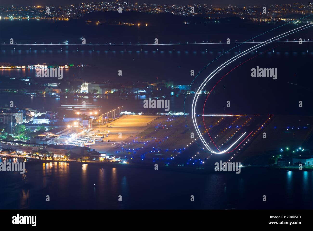 Aéroport Santos Dumont de Rio de Janeiro la nuit au Brésil. Exposition longue montrant les traces de lumière de l'avion pendant le décollage. Départ de l'avion sur une piste lumineuse. Banque D'Images
