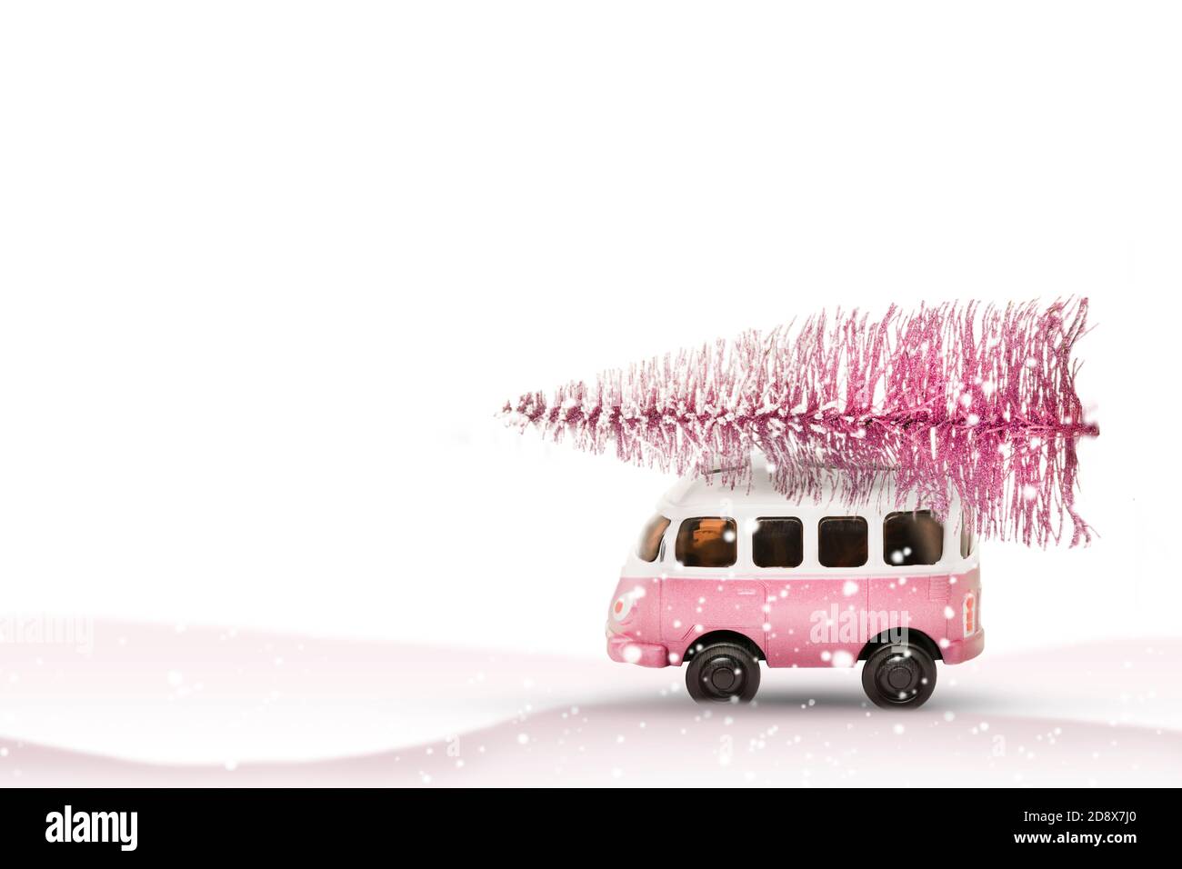 La voiture de bus jouet transporte un arbre de Noël de la forêt. Couleurs rose et blanc, vacances d'hiver nouvel an humeur Banque D'Images