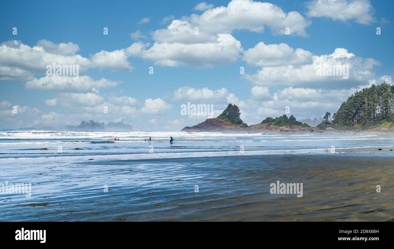 Les surfeurs se dirigeant vers l'océan Pacifique à Cox Bay Beach, dans le parc national Pacific Rim, sur l'île de Vancouver, en Colombie-Britannique, au Canada, sous Blue Sky Banque D'Images