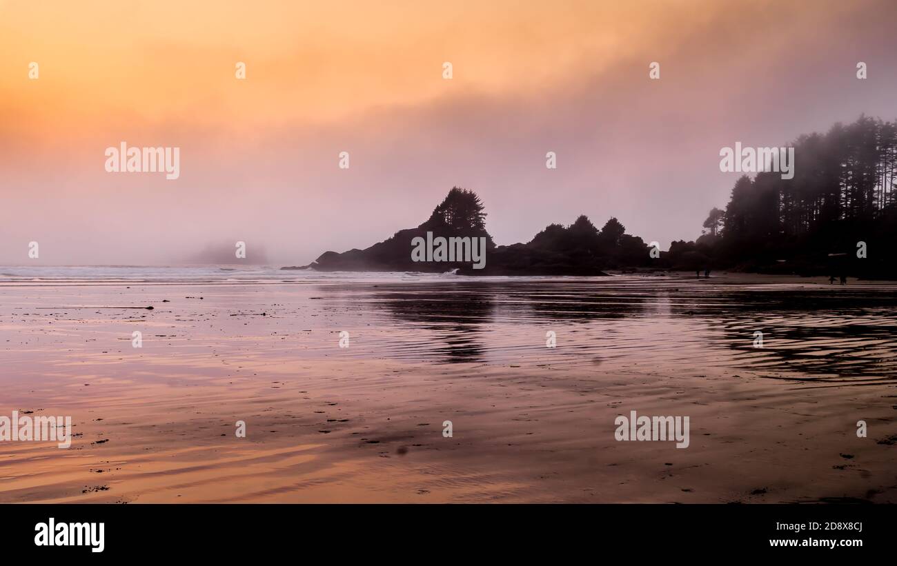 Coucher de soleil créant une lueur d'orange sur le brouillard qui est suspendu au-dessus de l'océan Pacifique à Cox Bay au parc national Pacific Rim sur l'île de Vancouver, BR Banque D'Images