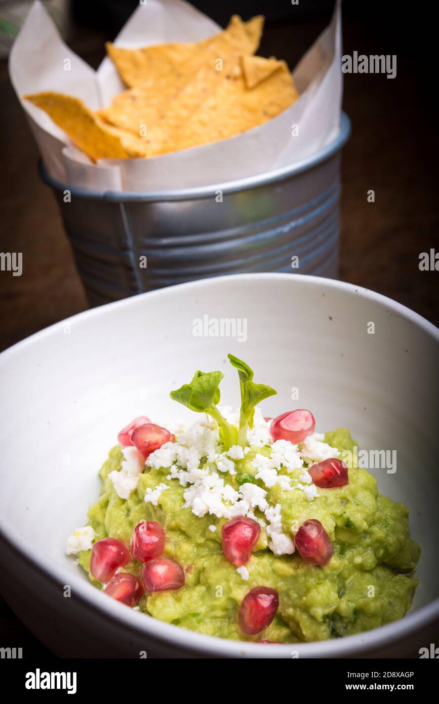 Sauce à la guacamole servie avec des nachos avec des ingrédients et de la grenade Banque D'Images