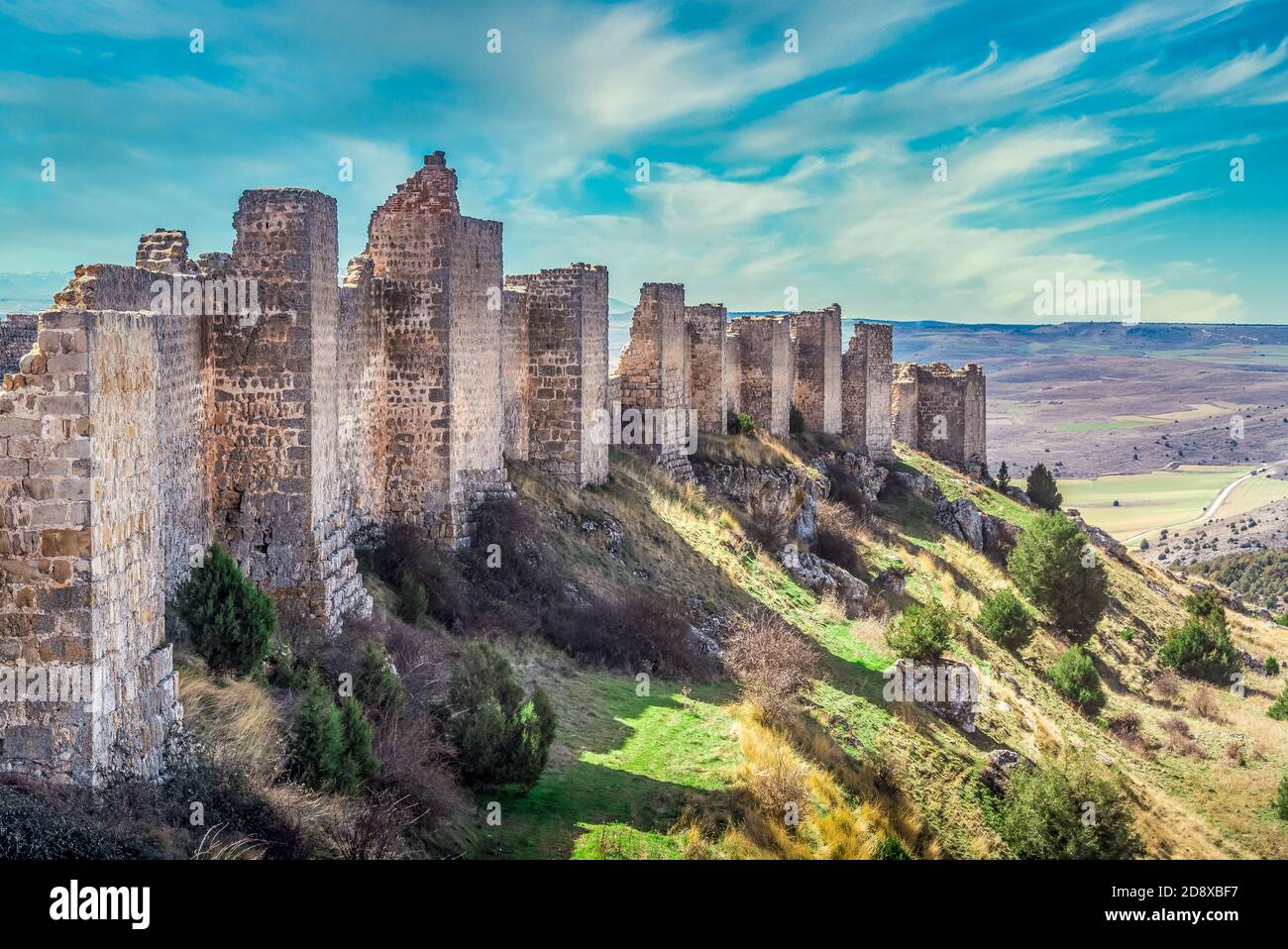 Rangée de tours carrées projetant des murs et de la coulée Ombre sur la colline au château médiéval de Gormaz en Espagne avec un ciel bleu ciel nuageux Banque D'Images
