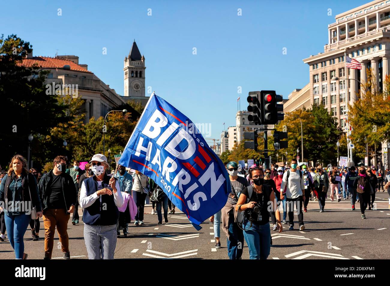 Le manifestant de la Marche des femmes porte un drapeau de Biden Harris sur Penn Avenue avec la tour de l'hôtel Trump au loin, Washington, DC, USA Banque D'Images