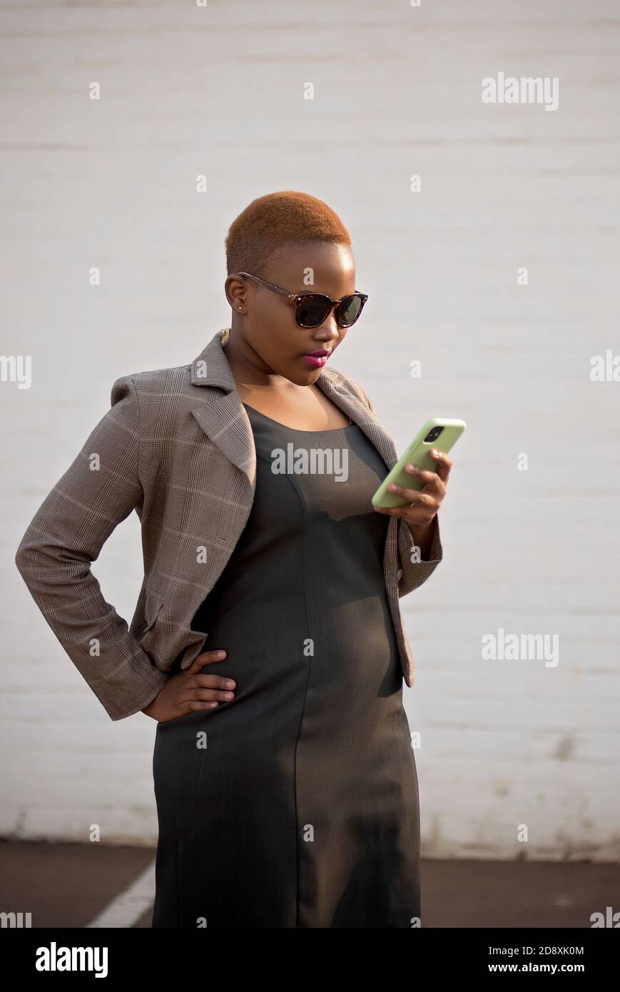femmes noires d'entreprise dans un environnement naturel avec talons et soleil des lunettes sur son chemin pour travailler avec le téléphone Banque D'Images