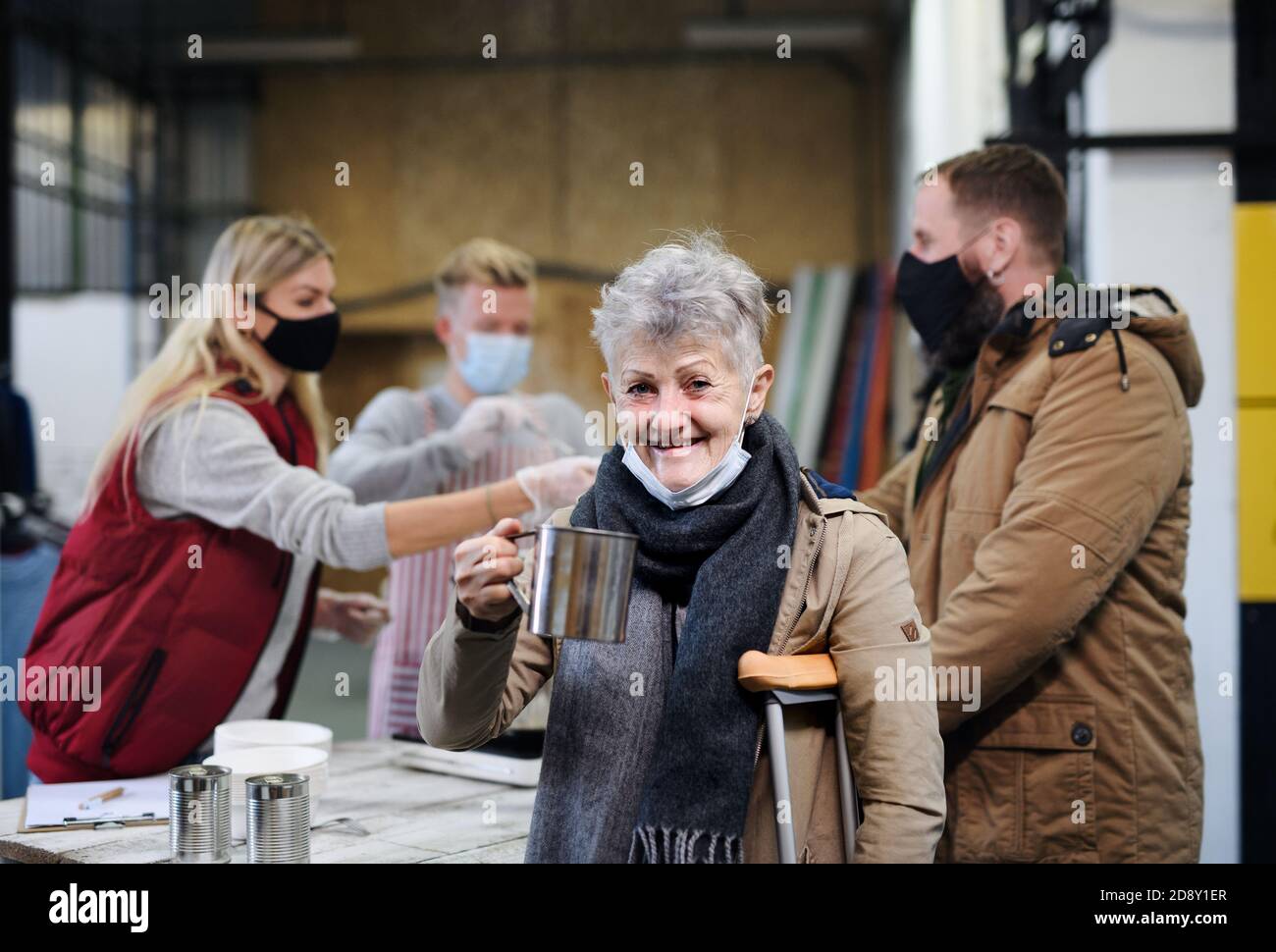 Bénévoles servant de la soupe chaude pour les sans-abri dans un centre de dons de charité communautaire, concept de coronavirus. Banque D'Images