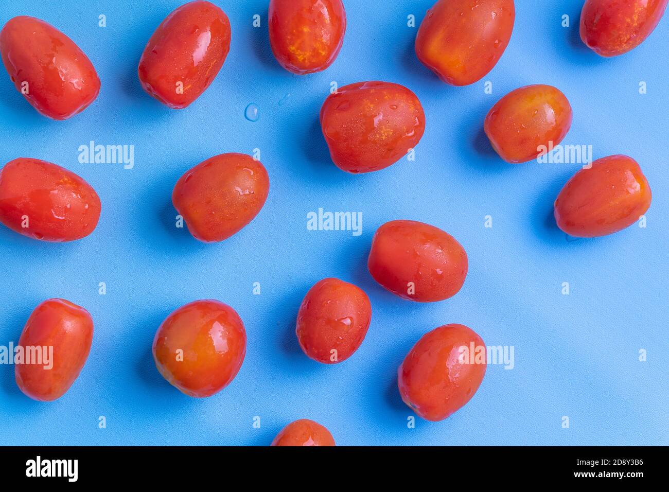 Groupe de tomates cerises isolées sur fond bleu. Groupe de tomates cerises fraîches empilées isolées sur fond bleu. Banque D'Images