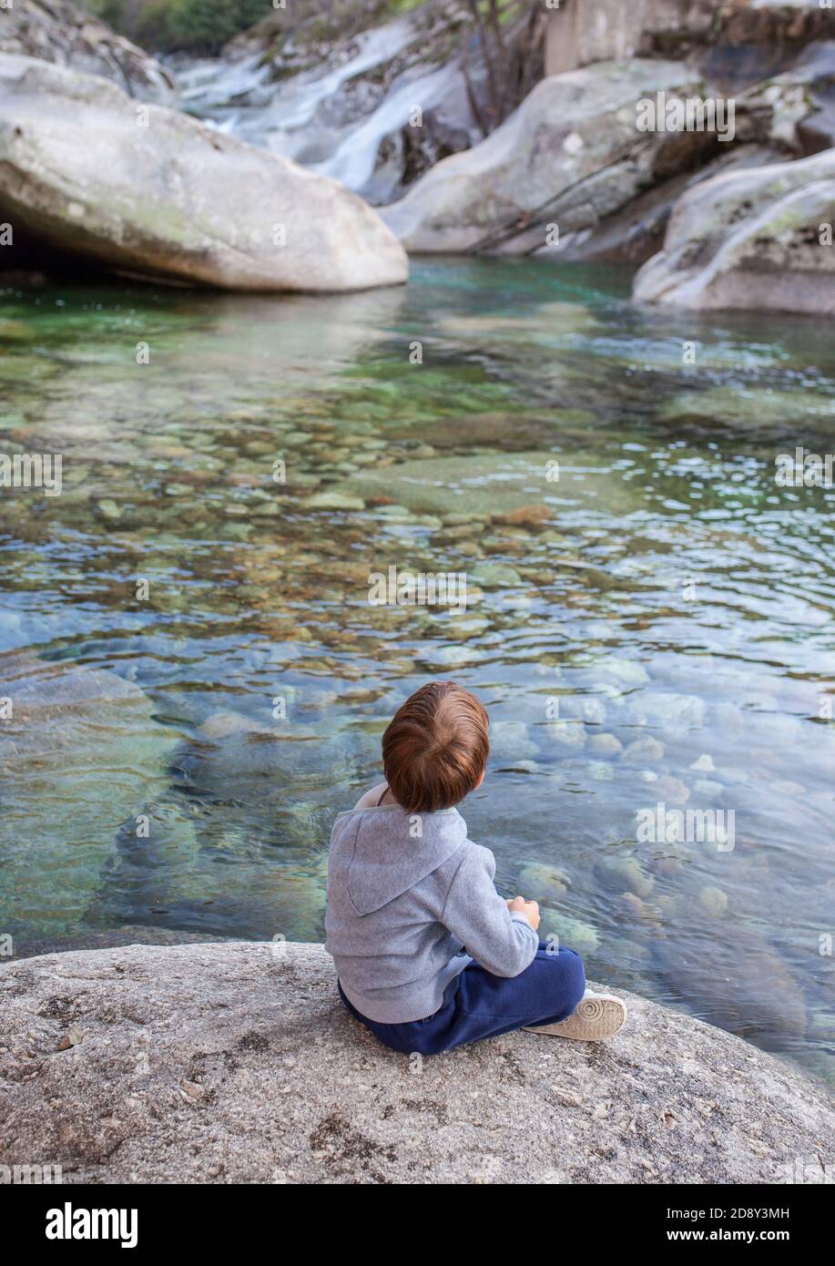 Petit garçon assis au bord de la rivière de Los Pilones gorge à la réserve naturelle Garganta de los Infiernos. Endroit exceptionnel pour profiter de la nature Estrémadure Banque D'Images