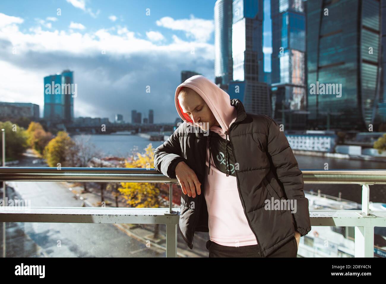 Beau homme décontracté en veste noire et pull à capuche rose debout sur une  vue de gratte-ciel. Concept de pensée Photo Stock - Alamy