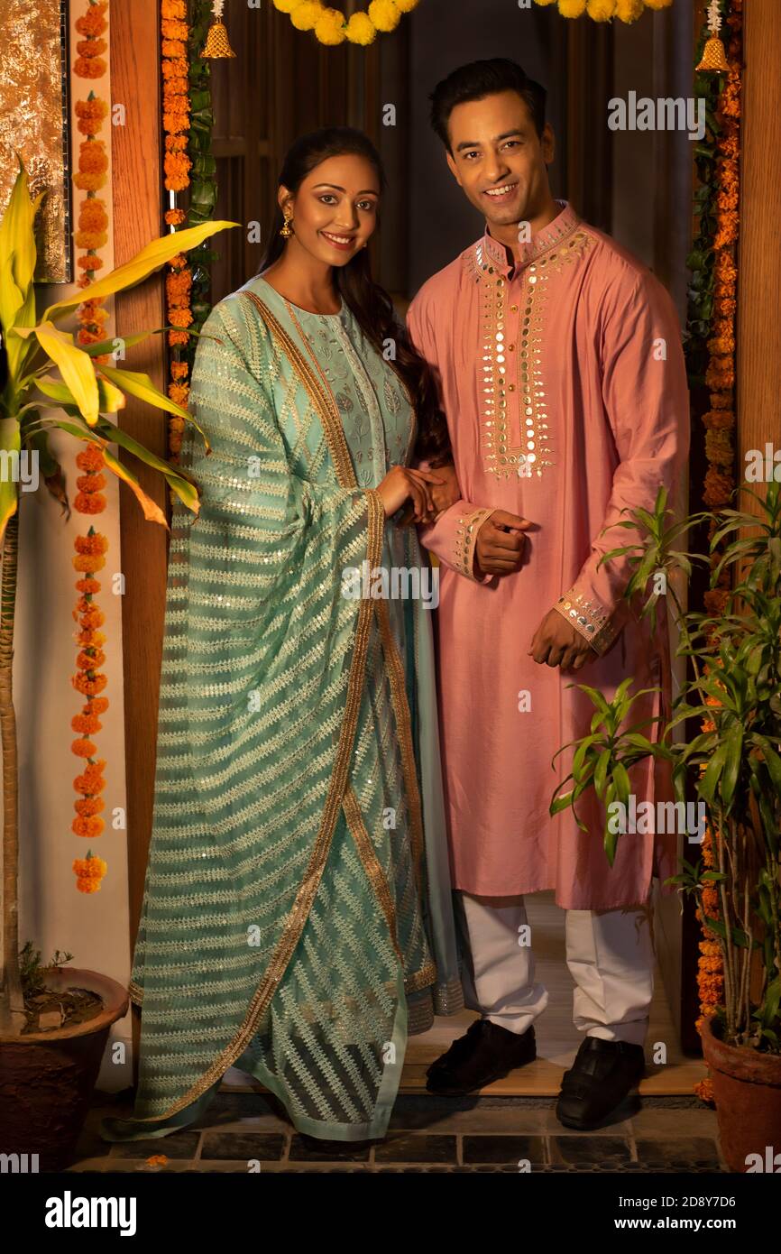 UN MARI ET UNE FEMME SE POSANT AVEC JOIE À UNE ENTRÉE DÉCORÉE PORTE Banque D'Images