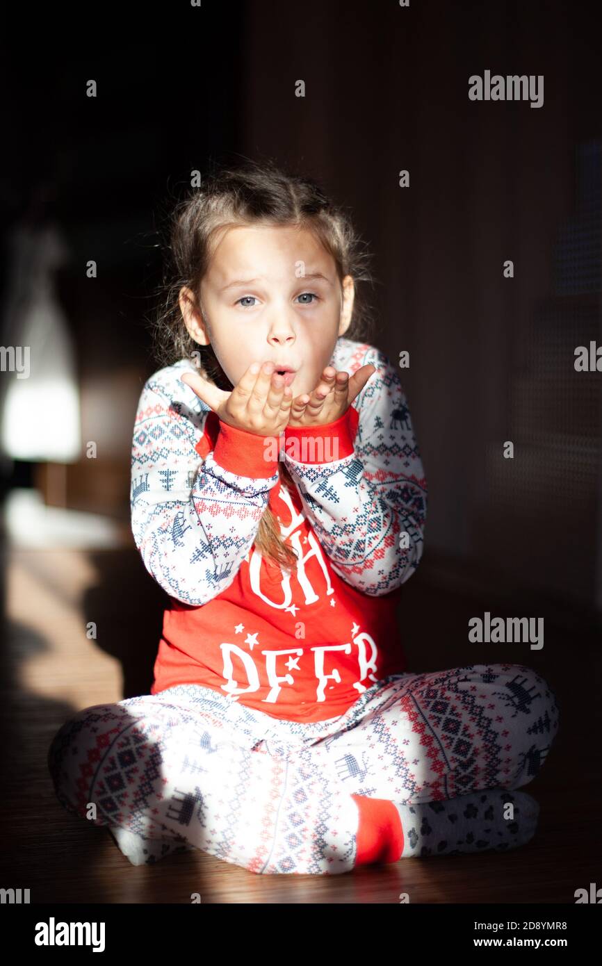 Une fillette de Noël pigeonnée se trouve sur le sol et souffle un baiser, le matin du nouvel an Banque D'Images
