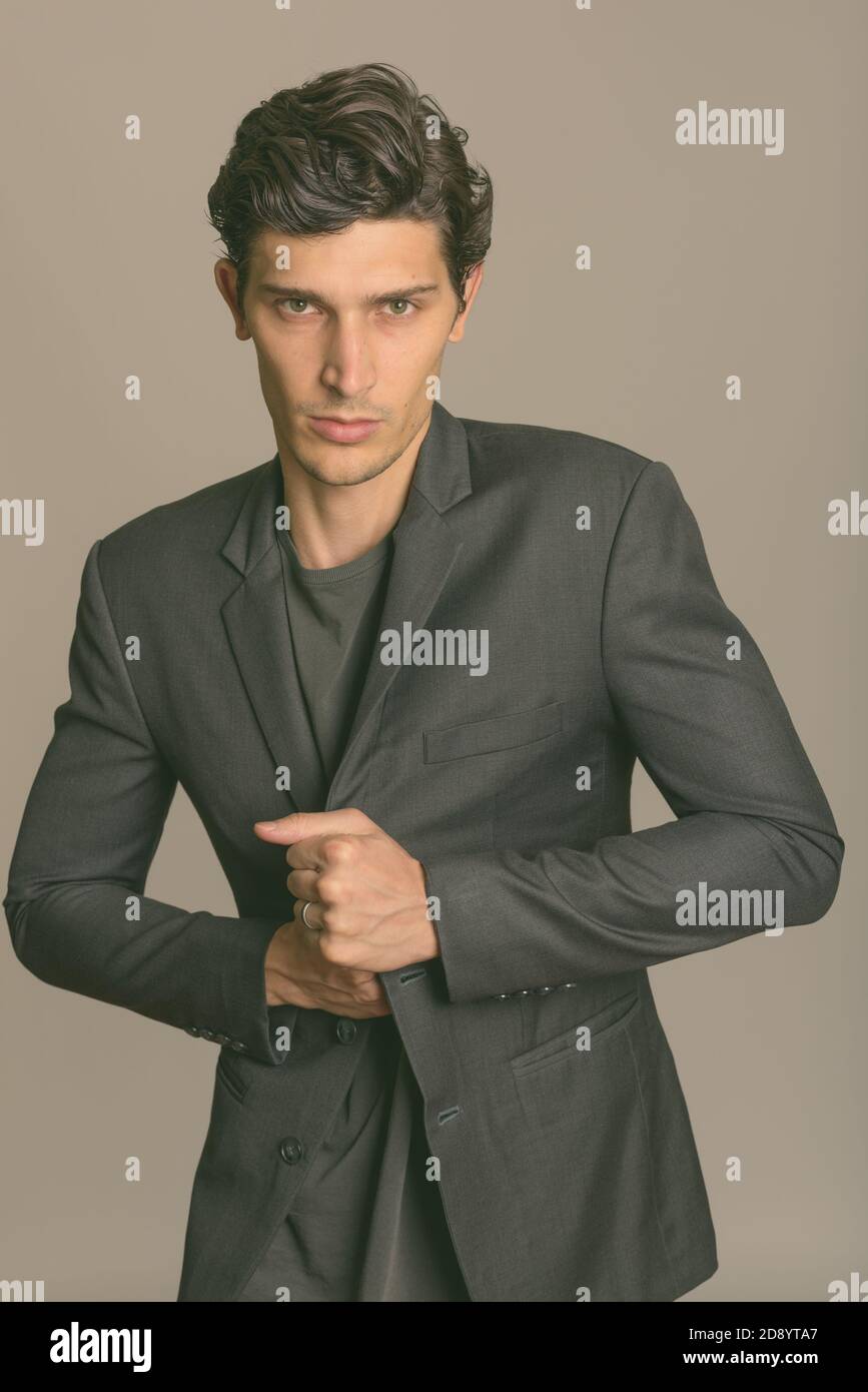 Photo studio d'un jeune homme d'affaires élégant tenant une veste sur fond gris Banque D'Images