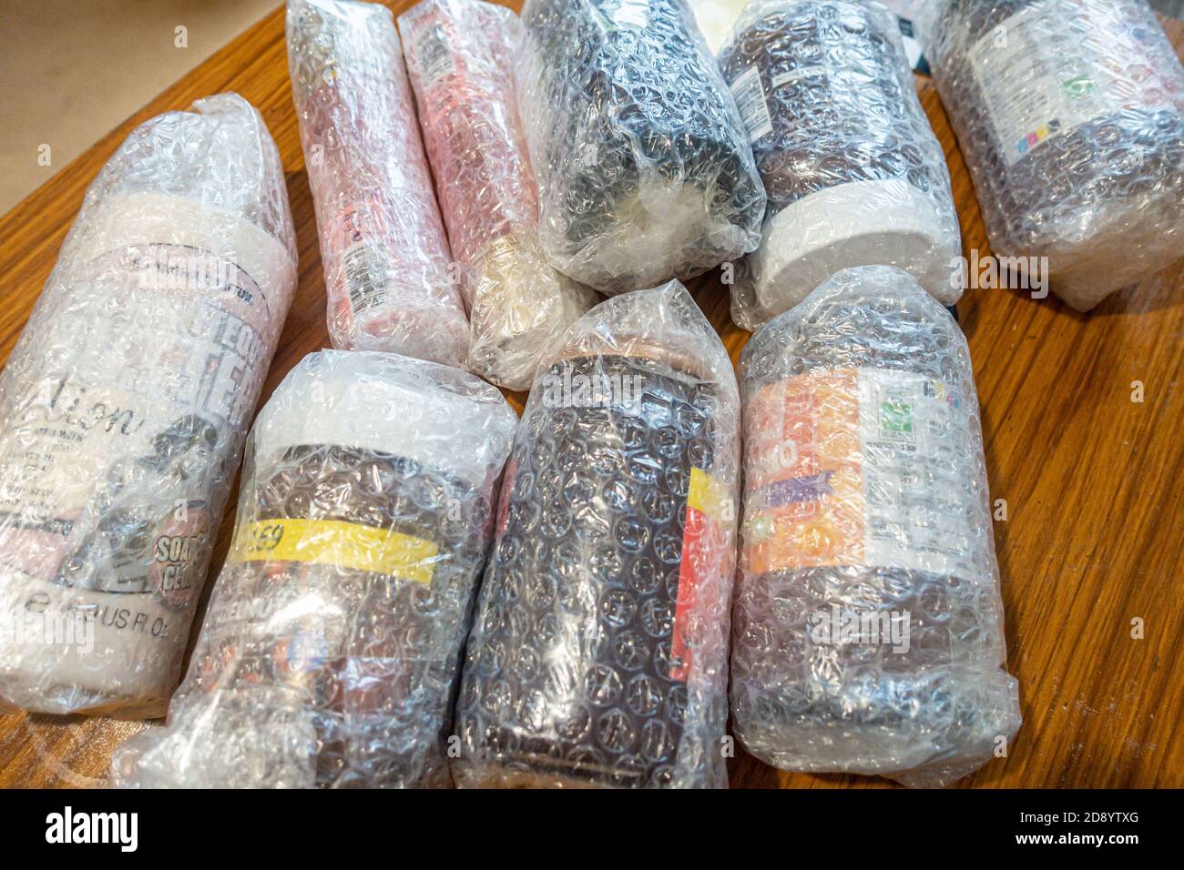 Pots en verre et bouteilles de lotion enveloppés dans un film à bulles à mettre dans une boîte de balikbayan envoyée par un philippin à l'étranger à des parents aux Philippines. Banque D'Images