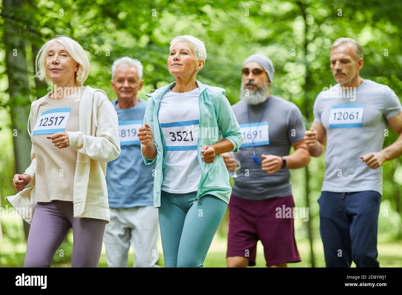 Des hommes et des femmes âgés actifs qui passent la journée d'été ensemble au marathon de course au parc, tir moyen long Banque D'Images