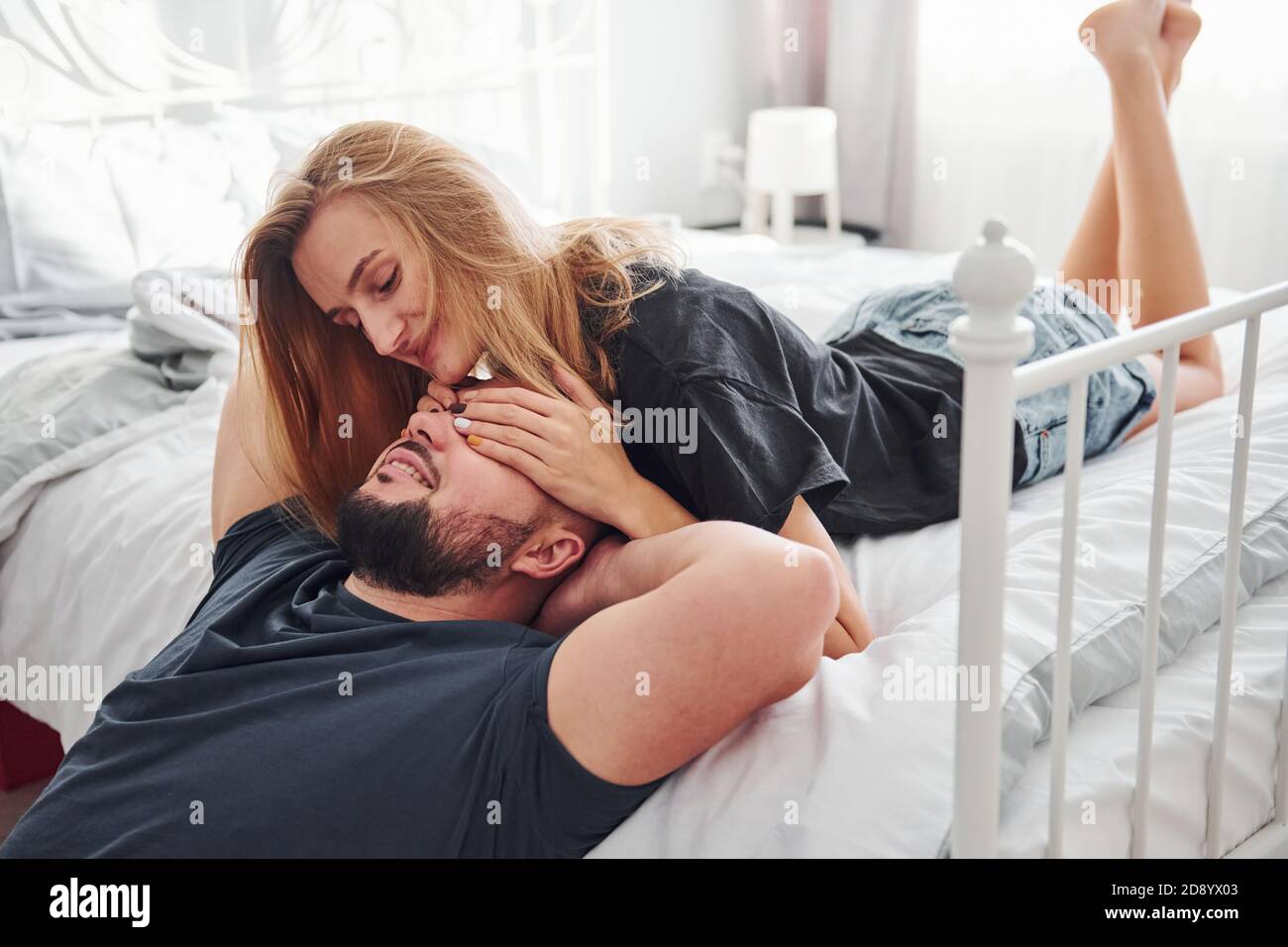 Un jeune couple marié s'embrasse dans la chambre à coucher pendant la journée Banque D'Images