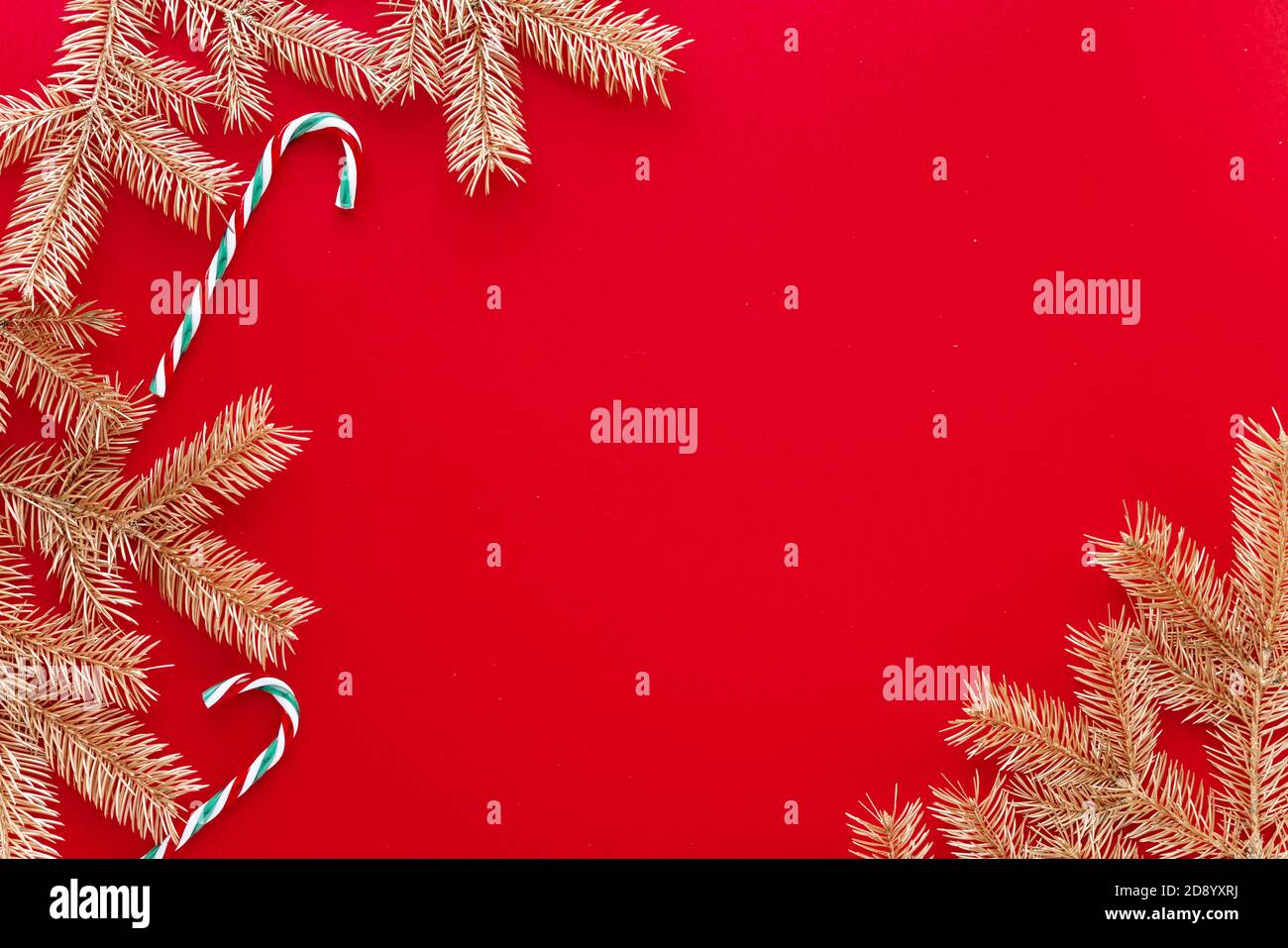 Arrière-plan de Noël ou de nouvel an rouge, composition simple de branches de sapin d'or et jouets de noël, Flatlay, espace vide pour le texte de salutation. Banque D'Images