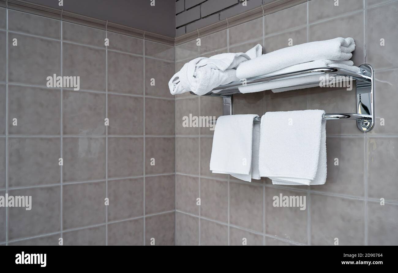 Serviettes blanches sur un cintre dans la salle de bains contre le arrière-plan d'un mur en mosaïque Banque D'Images