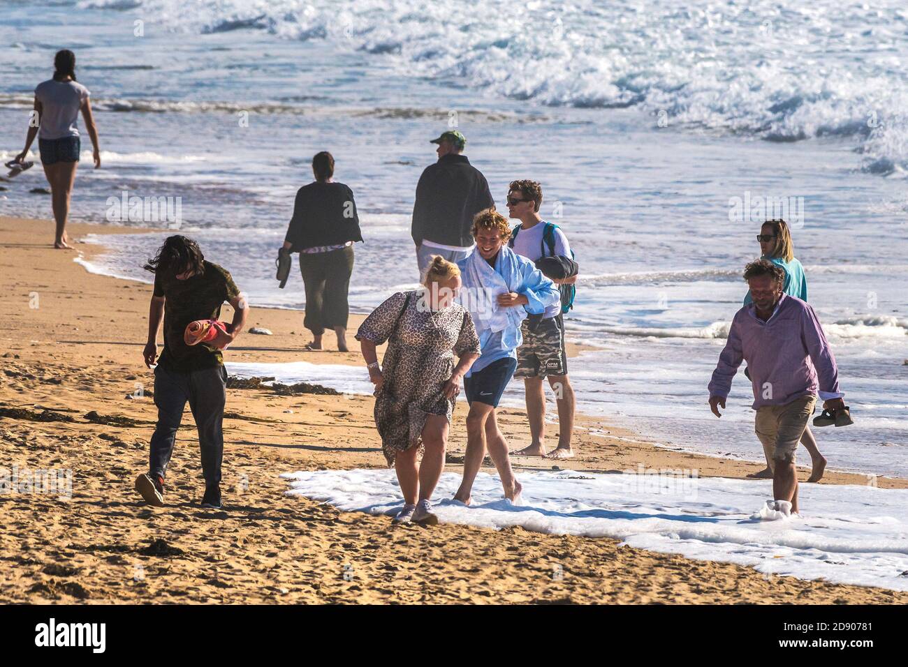 Vacanciers en vacances lors d'une promenade de vacances à pied comme la marée arrive sur la plage de Fistral à Newquay en Cornouailles. Banque D'Images