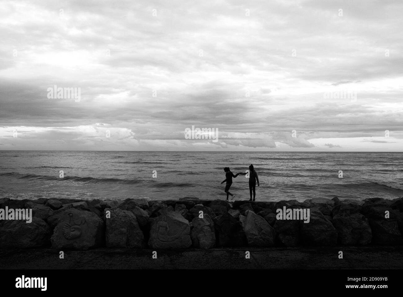 Les enfants marchent ensemble sur une falaise près de la mer, avec un ciel nuageux Banque D'Images