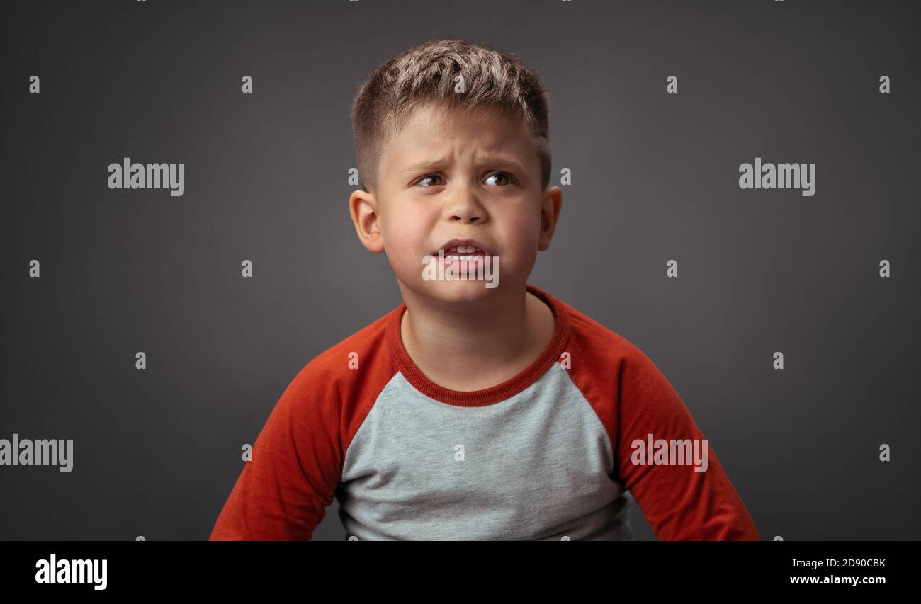 Tres Mignon Petit Garcon Avec Expression Confuse En Colere Sur Le Visage L Enfant Est Bouleverse Triste Concentre Et Serieux Decouper Sur Fond Gris Photo Stock Alamy