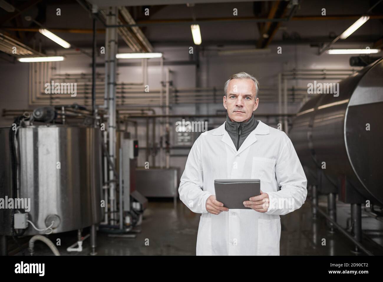 Portrait d'un homme mûr portant une blouse de laboratoire et regardant l'appareil photo pendant qu'il travaille dans la production alimentaire, dans l'espace de copie Banque D'Images