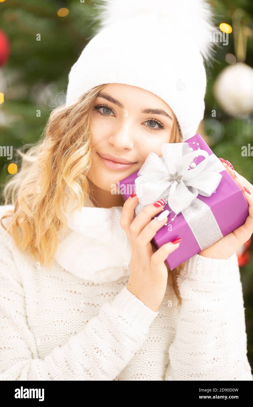 Belle fille en chandail blanc et casquette tient un cadeau de Noël  soigneusement emballé souriant Photo Stock - Alamy