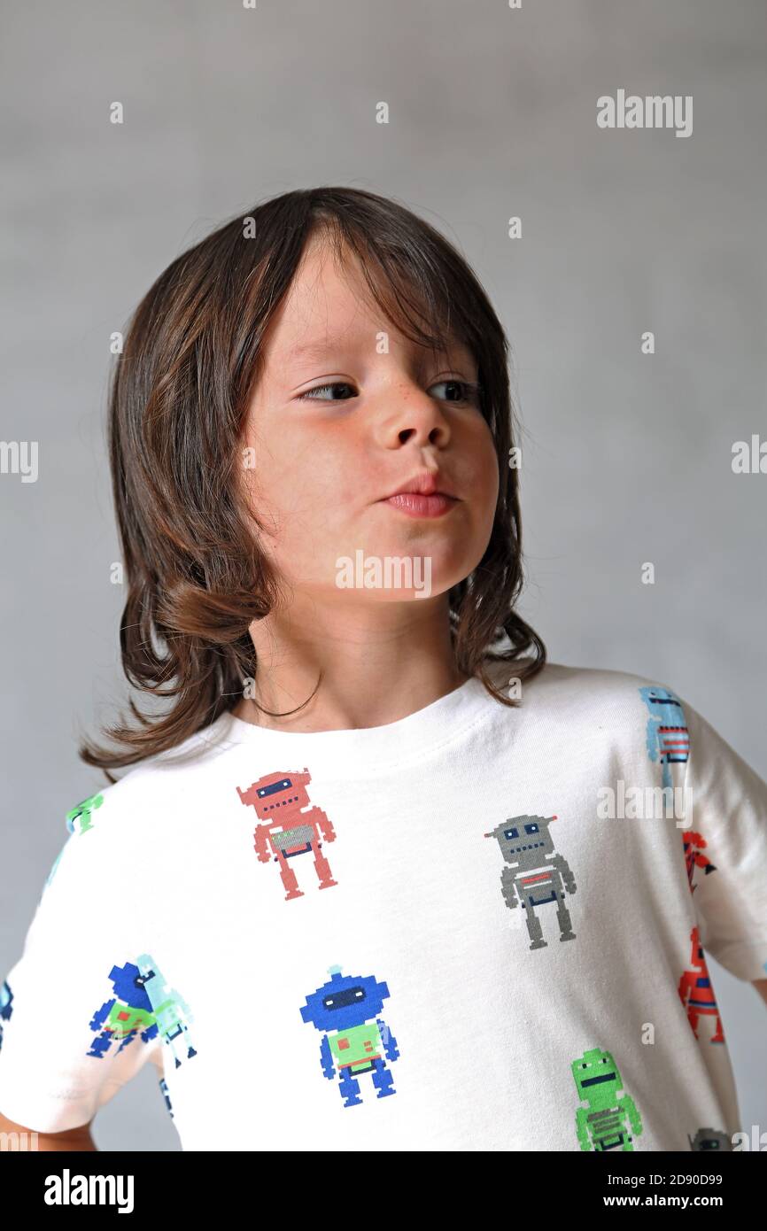 Portrait d'un garçon de 8 ans, avec des cheveux longs qui s'en vont avec un t-shirt avec des robots. ©PRWPhotography Banque D'Images
