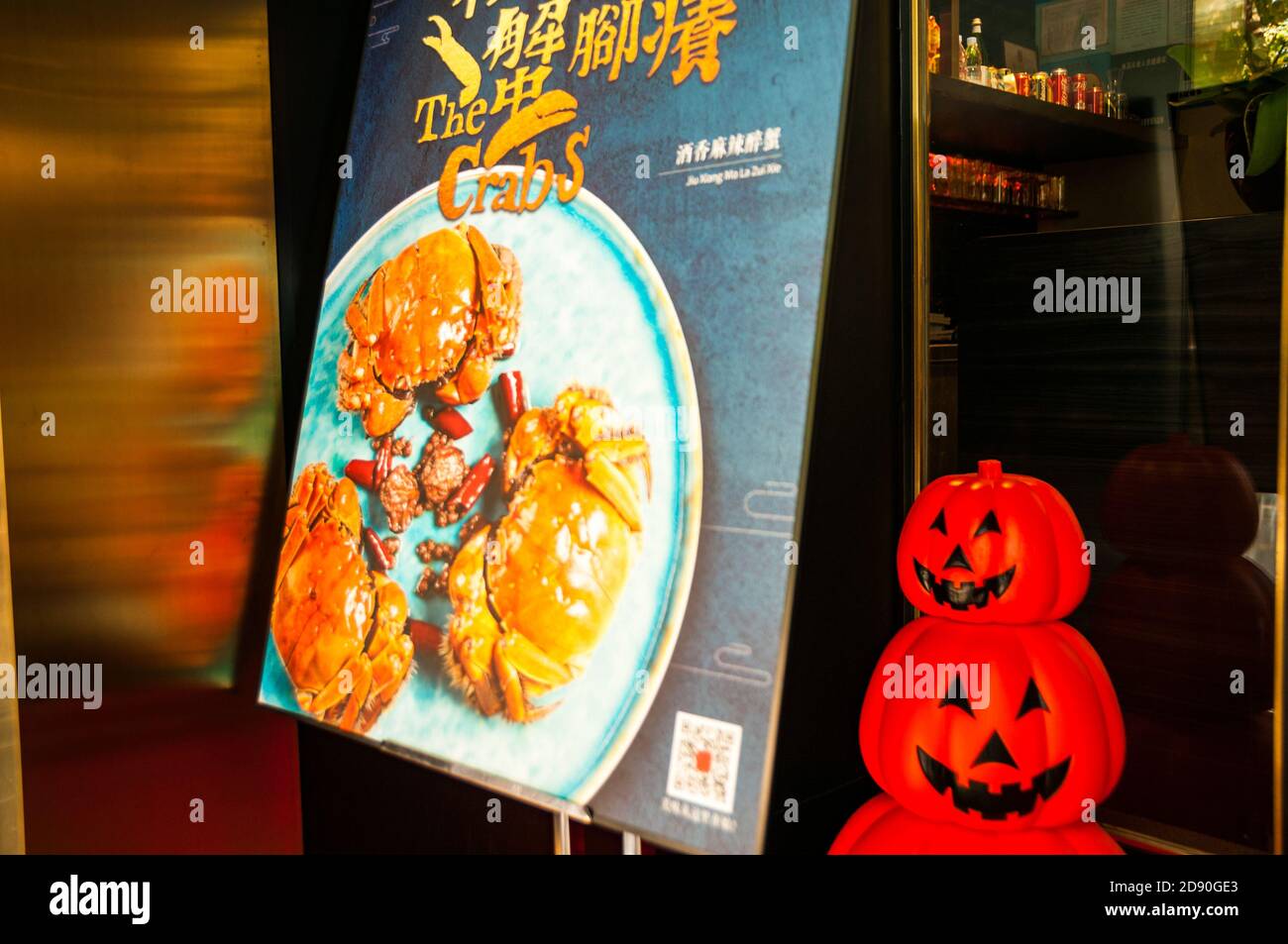 Un panneau annonçant des crabes poilus dans un restaurant sur la route Fumin de Shanghai avec des décorations de citrouille effrayantes derrière pour Halloween. Banque D'Images