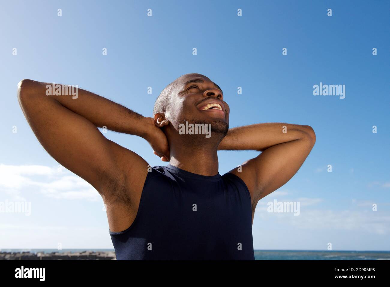 Portrait d'un jeune homme noir heureux et en bonne santé souriant avec les mains derrière la tête Banque D'Images
