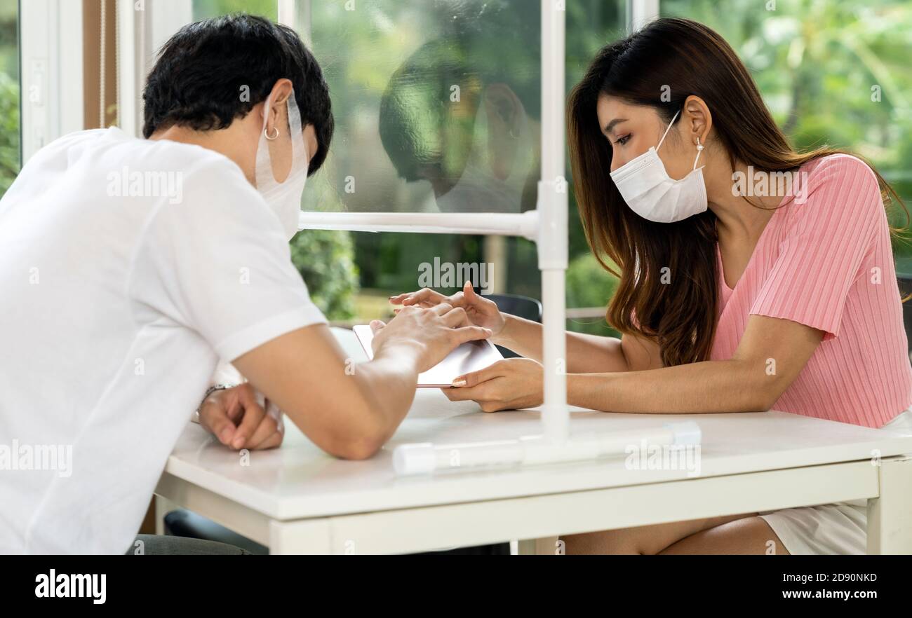 Un couple asiatique recherche un menu de tablette numérique. Ils se sont assis sur une table de distanciation sociale pour un nouveau style de vie normal au restaurant après le coronavirus Banque D'Images