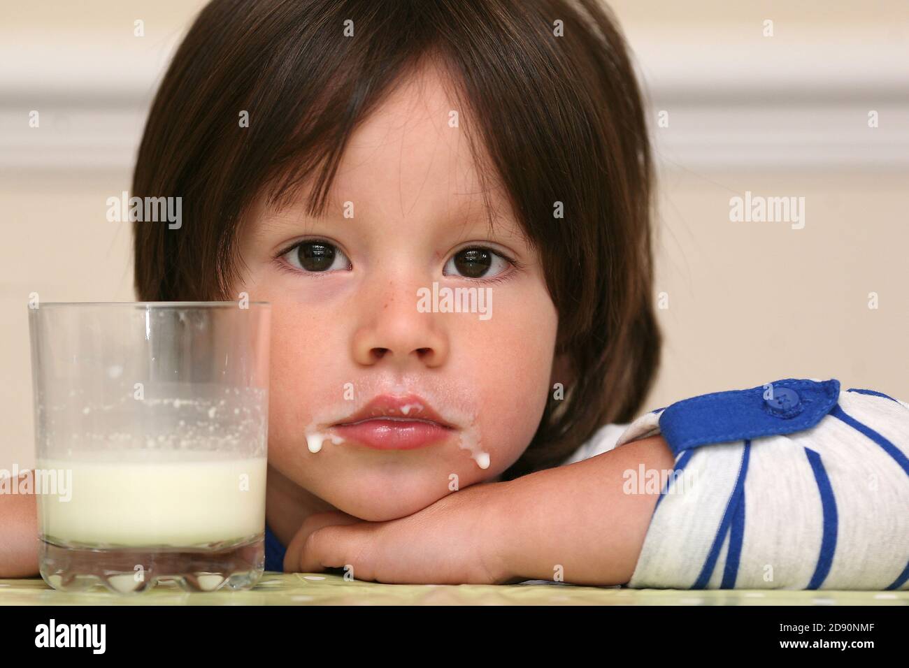 Un petit garçon d'école juste après une grande bouchée de lait à la table de petit déjeuner avec un verre de lait frais, Powys, pays de galles. ©PRWPhotography Banque D'Images
