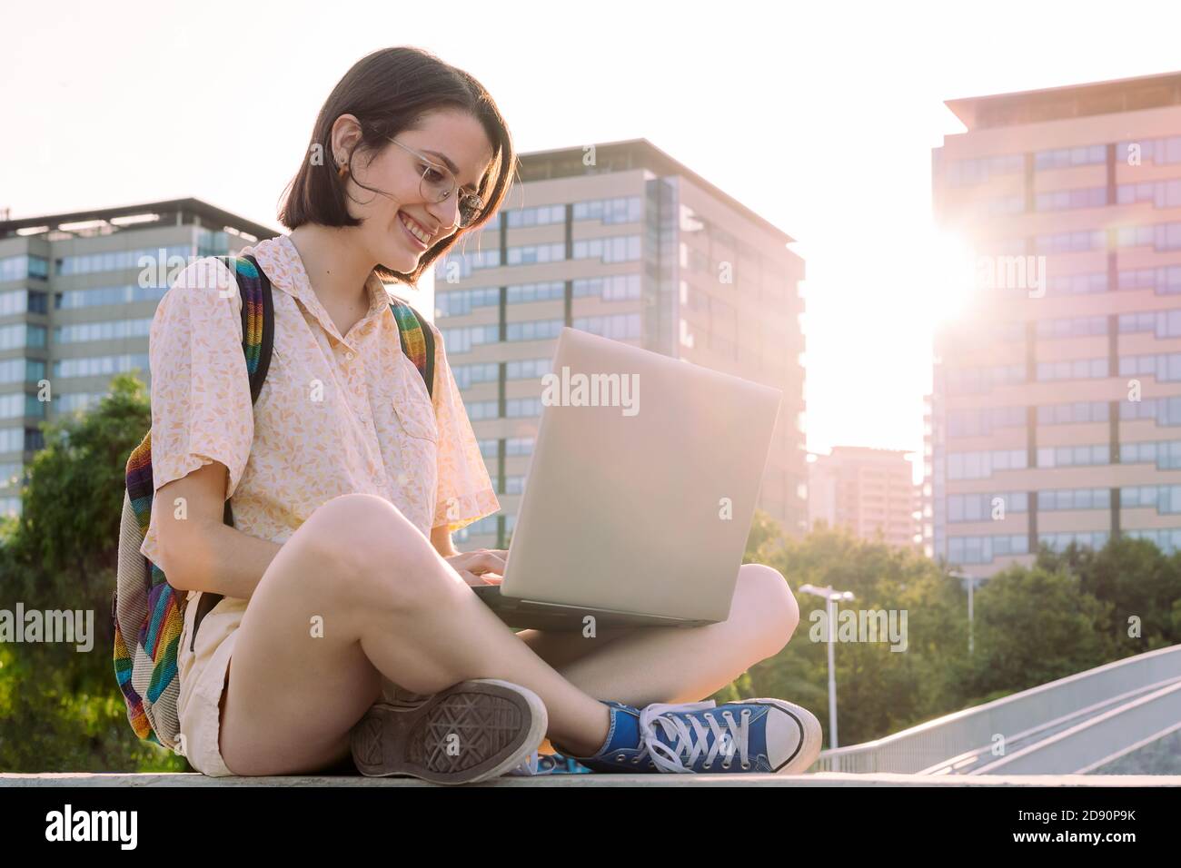 jeune voyageur heureuse femme avec sac à dos assis dans la ville dactylographiant sur son ordinateur, concept de la technologie, jeune et numérique nomade style de vie, copie sp Banque D'Images