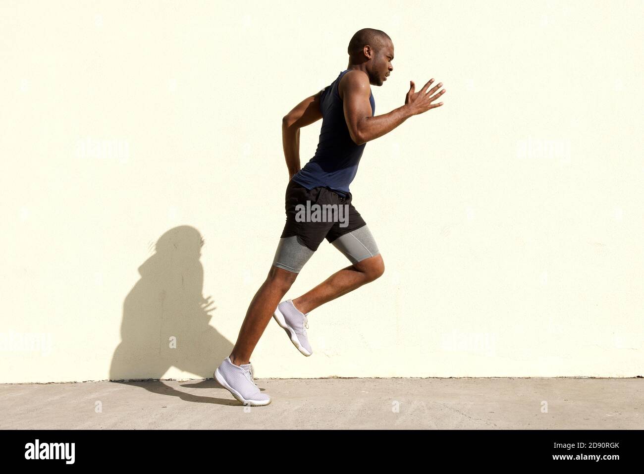 Portrait complet du profil du corps de jeune homme noir en bonne santé courant par mur Banque D'Images