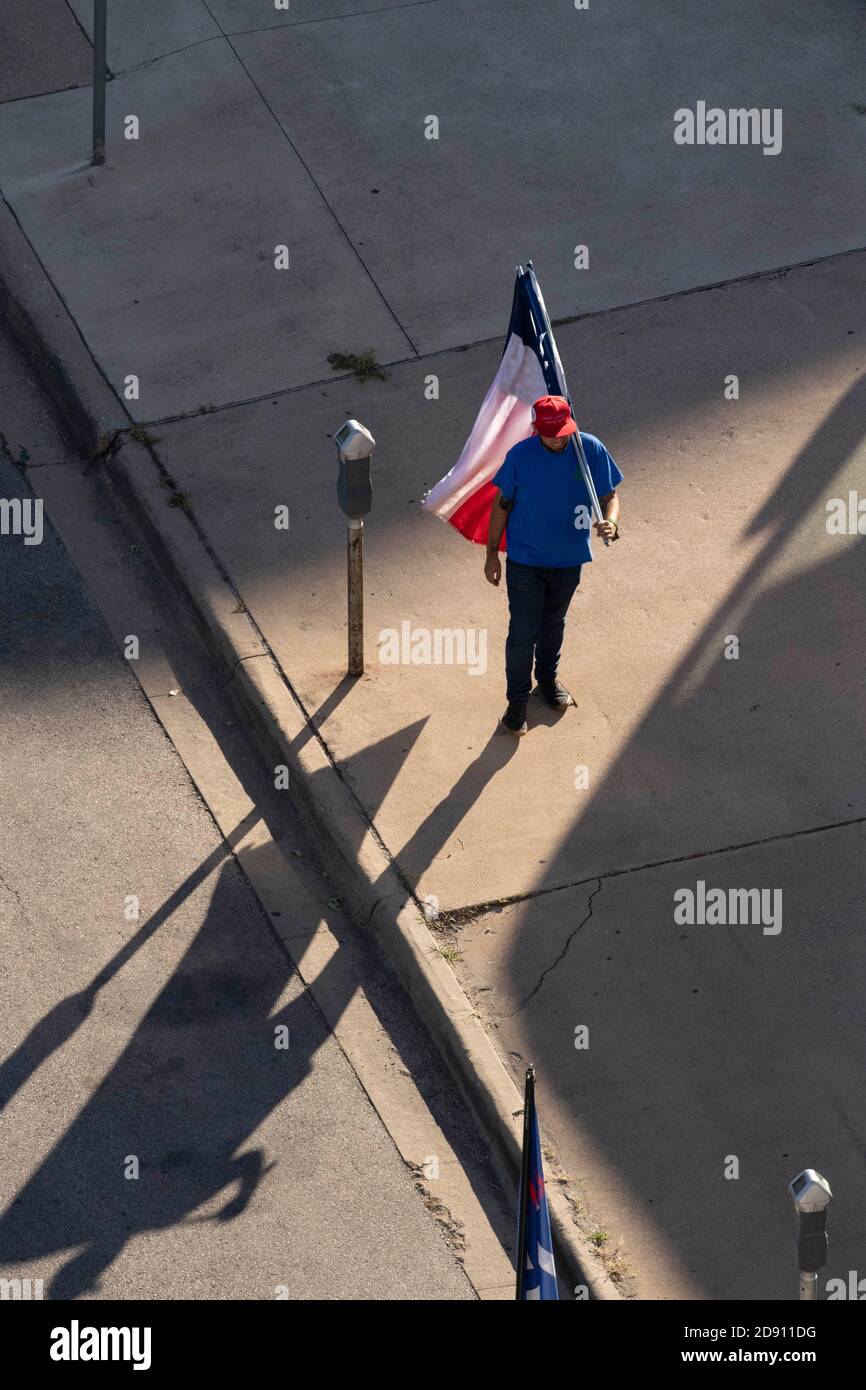 Austin, TX USA 30OCT20: Un partisan de Trump avec un drapeau américain et un drapeau du Texas modifié avec une feuille de marijuana à la place des défilés Lone Star tandis que d'autres bloquent un bus de campagne Biden-Harris au bureau AFL-CIO dans le centre-ville d'Austin. Le bus est arrivé à Austin à la suite d'un incident de circulation sur une autoroute bondée pendant qu'il voyageait de San Antonio. Les partisans de Biden à bord de l'autobus ont réclamé une douzaine de pick-up affiliés à Trump qui ont tenté de faire descendre l'autobus de la route. Plusieurs événements démocrates ont été annulés en raison de ces perturbations. Le FBI enquête sur l'incident. Banque D'Images