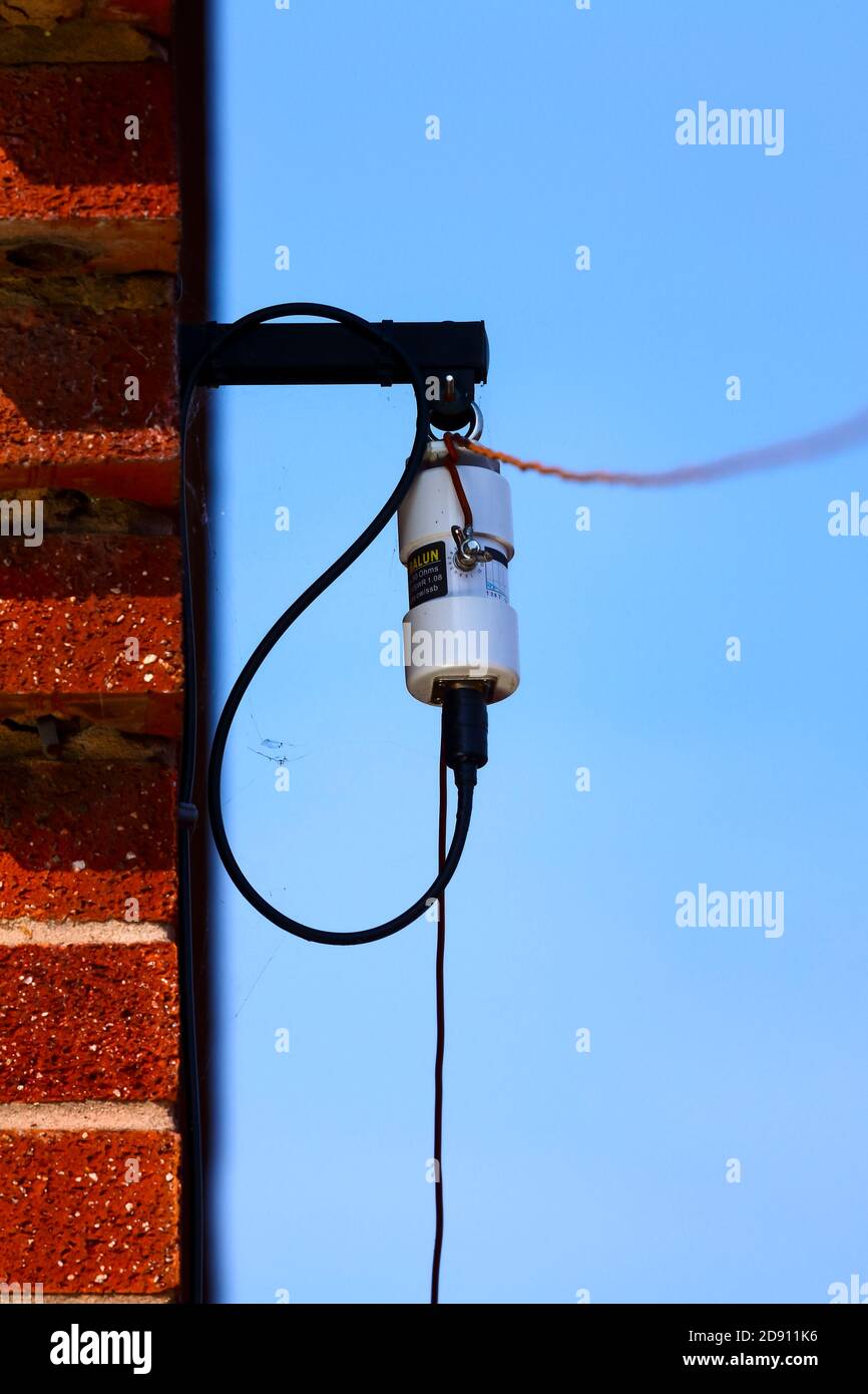 Antenne radio amateur à long fil HF dipôle et balun fixe sur le côté d'un mur de maison Banque D'Images