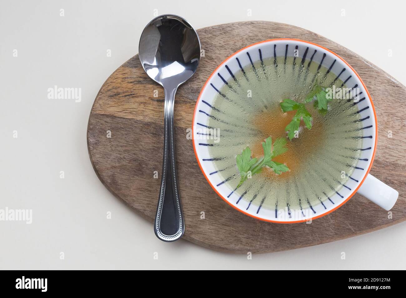 bouillon de poulet chaud minimaliste dans un bol à soupe blanc vue sur le dessus de la planche en bois Banque D'Images