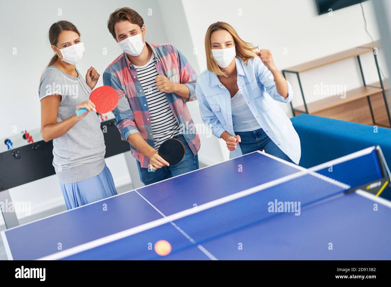 Groupe d'étudiants portant des masques jouant au tennis de table dans le campus Banque D'Images