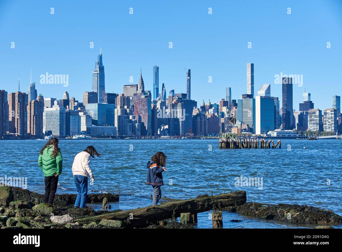 Enfants debout au bord de l'East River à Williamsburg, Brooklyn, NY, avec le Manhattan Skyline en arrière-plan. Banque D'Images