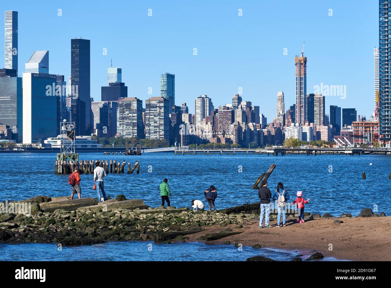 Les familles apprécient de se tenir au bord de l'East River à Williamsburg, Brooklyn, NY, avec les gratte-ciel de Manhattan en arrière-plan Banque D'Images