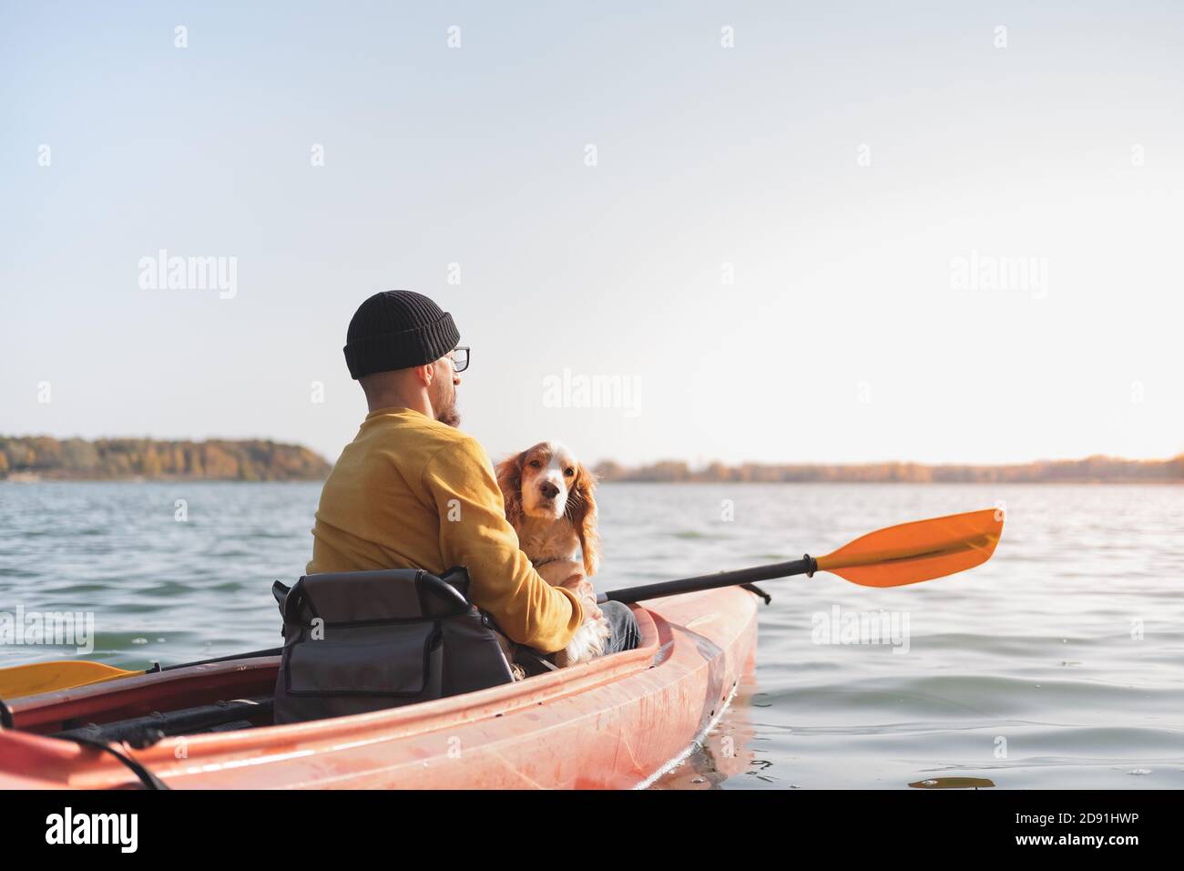 Homme avec un chien dans un canoë sur le lac. Jeune homme avec un épagneul dans un bateau de kayak, temps libre actif avec des animaux, compagnie, chiens d'aventure Banque D'Images