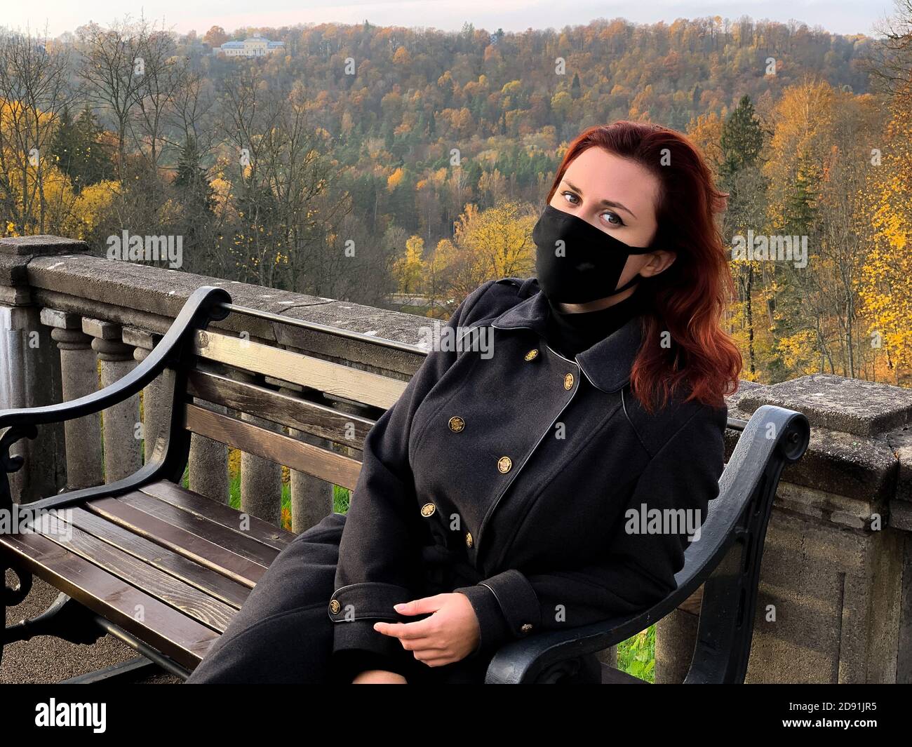 Triste jeune femme en noir masque médical regarde vous Banque D'Images