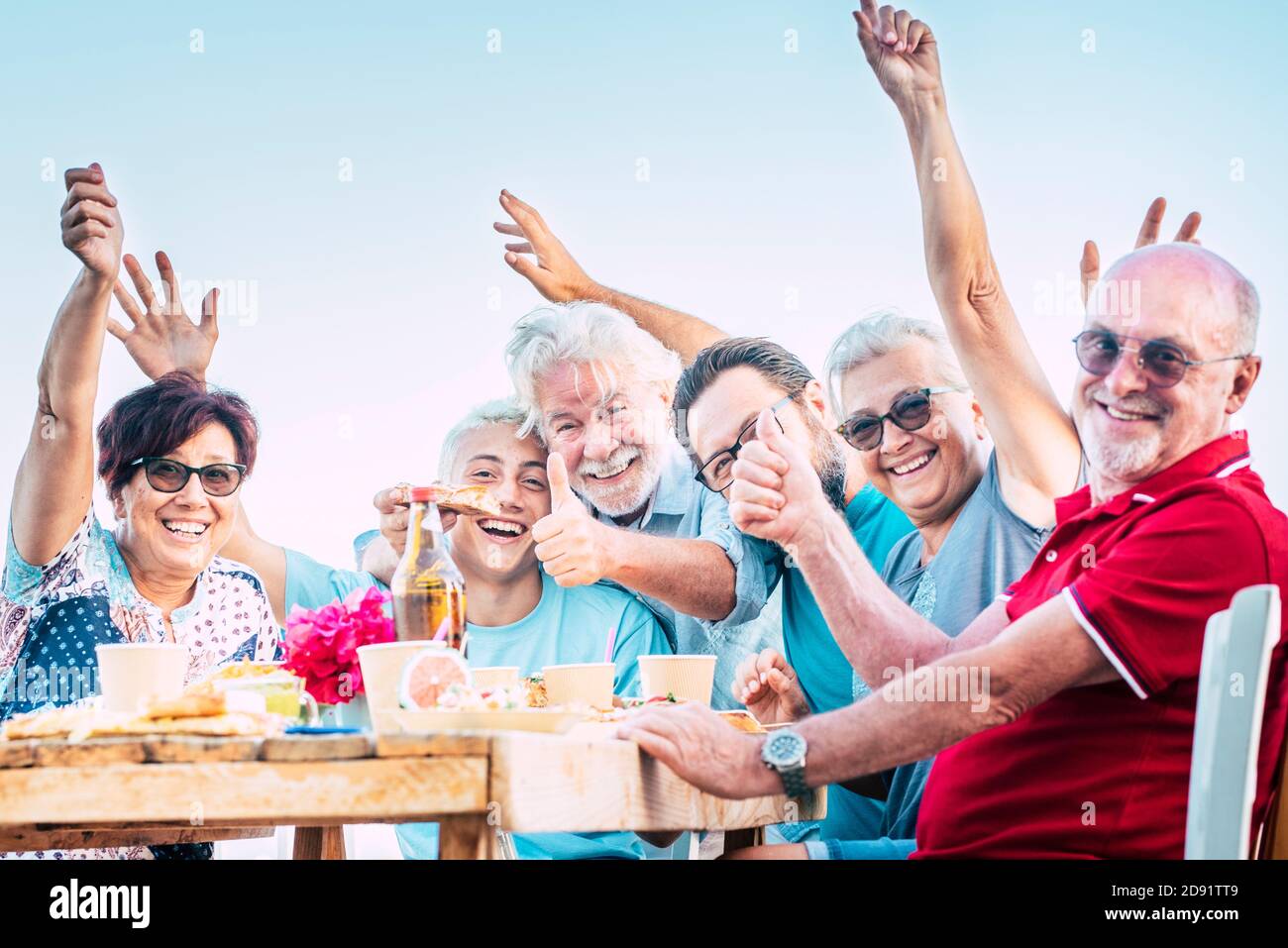 Groupe de personnes famille s'amuser et profiter de la fête en plein air - les hommes et les femmes caucasiens rient autour d'une table en bois avec plats et boissons - wi d'anniversaire Banque D'Images
