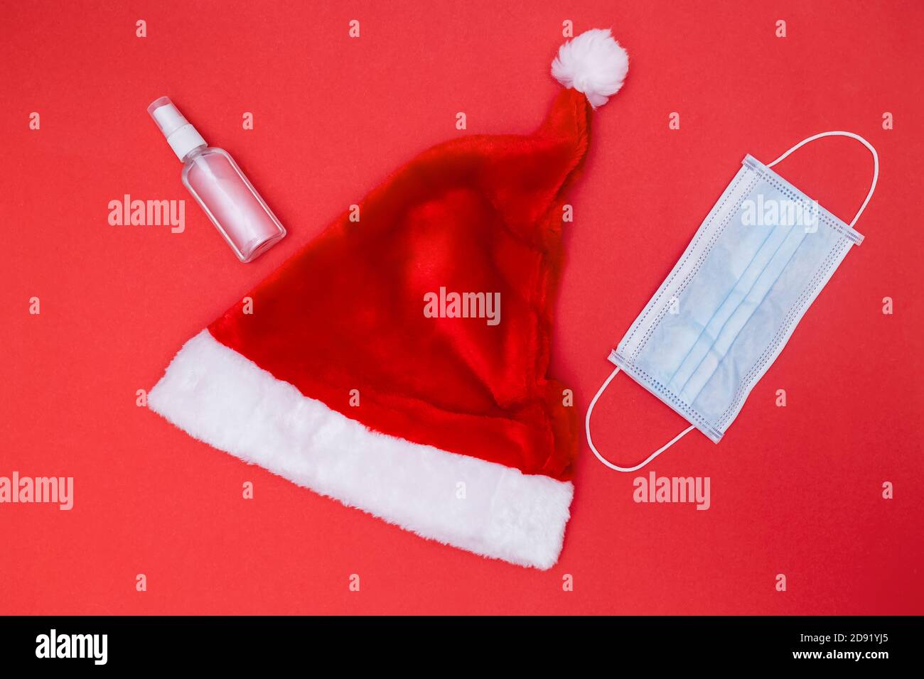 Chapeau et barbe du Père Noël avec masque sur le rouge arrière-plan Banque D'Images