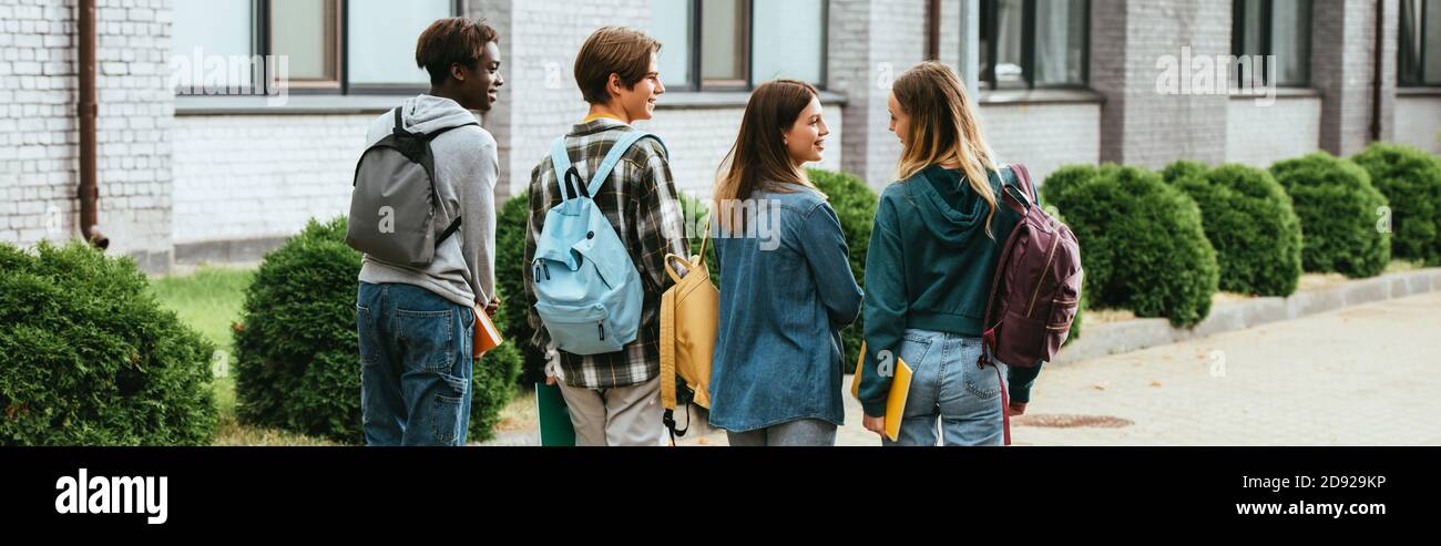 En-tête de site Web d'adolescents multiethniques souriants avec des sacs à dos marchant sur rue Banque D'Images
