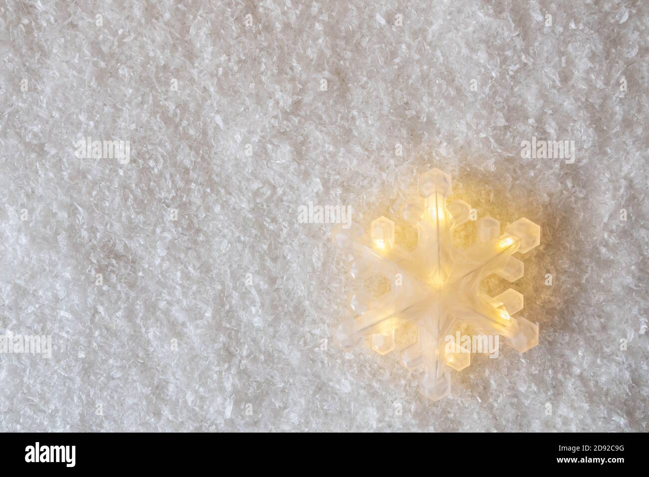Grand flocon de neige brillant sur fond imitation neige avec espace copie. Décoration d'ambiance de Noël. Décoration Minimali pour carte postale ou bannière Banque D'Images