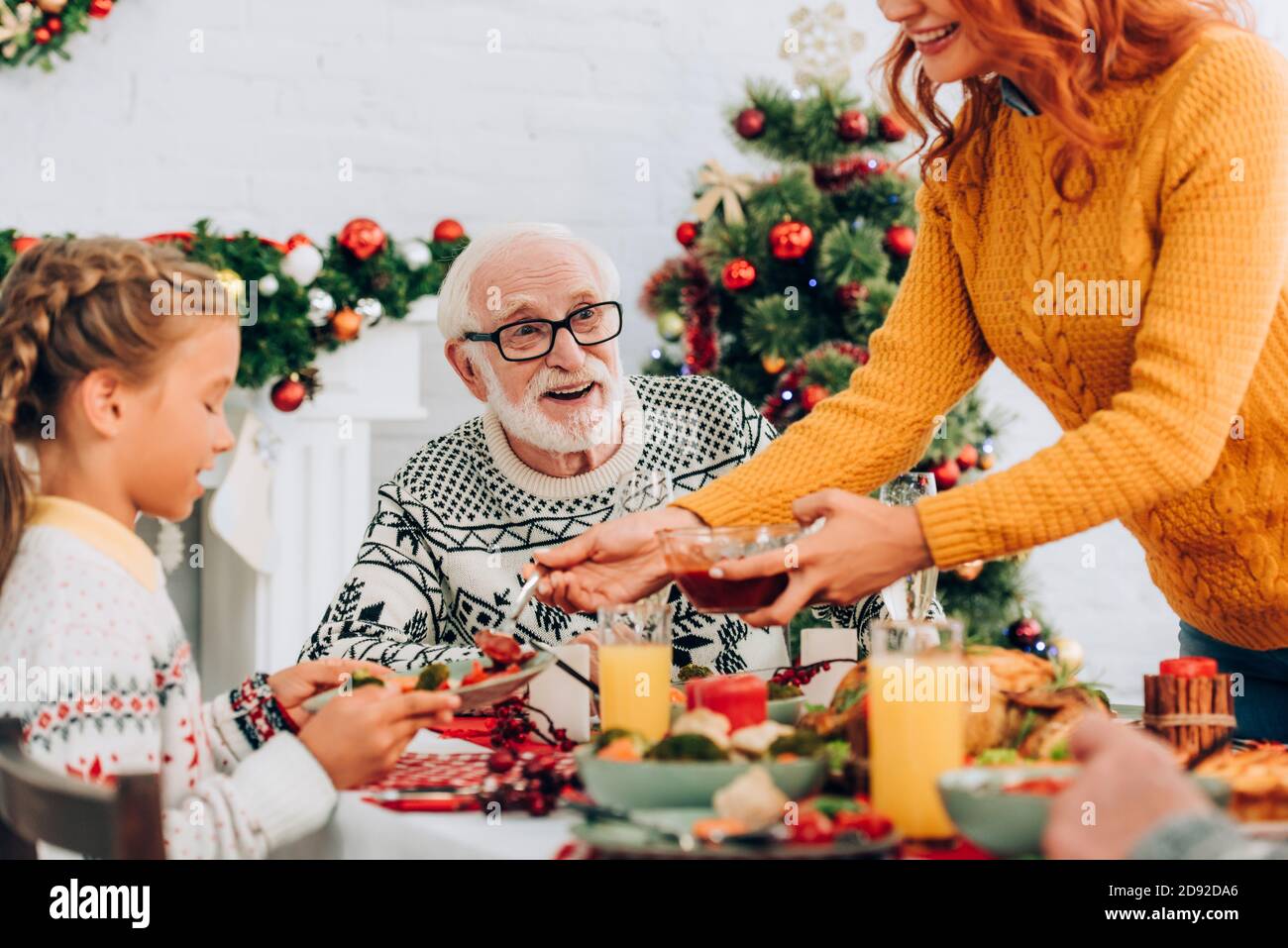 Foyer sélectif de grand-père heureux assis à table de fête avec famille Banque D'Images