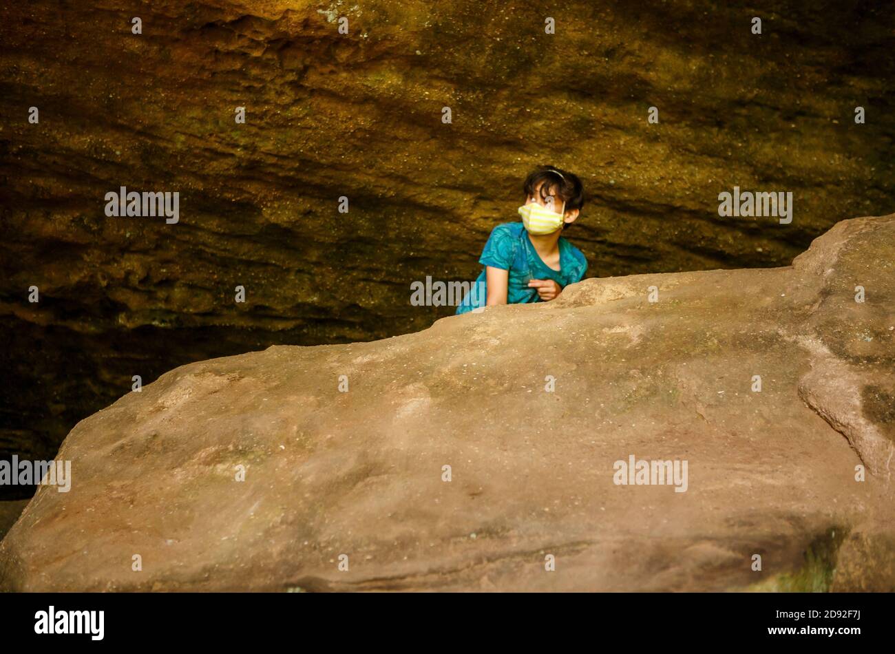 Un garçon portant le visage masque des pairs sur un grand rocher dans une gorge de grès Banque D'Images